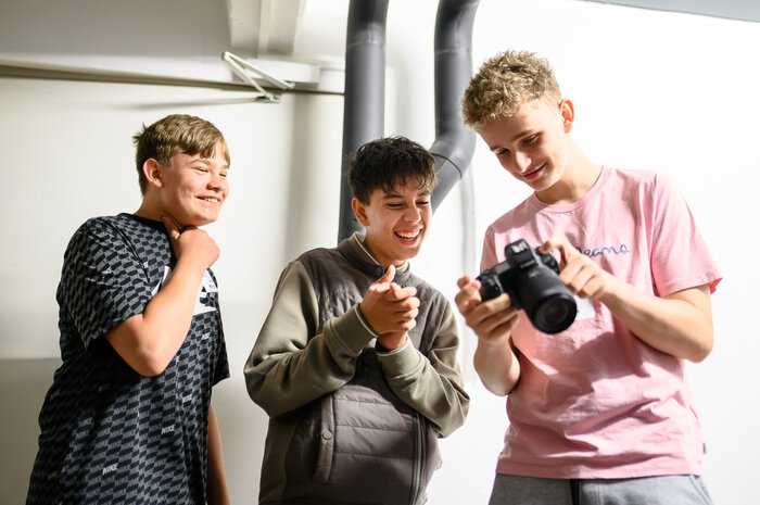 Bild von drei Jugendlichen mit einer Fotokamera bei der Jugenduni 2024