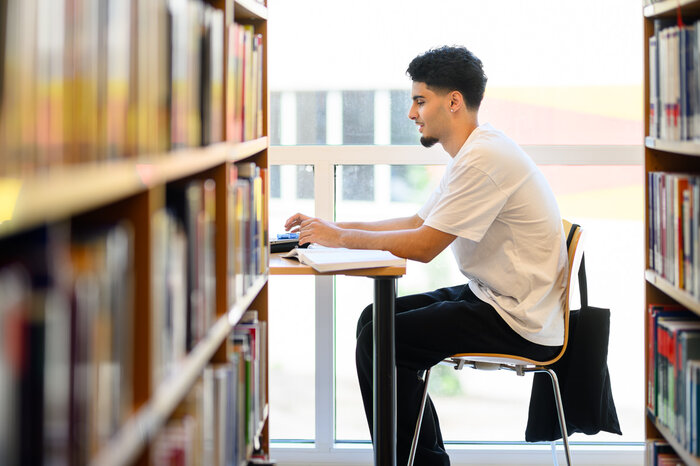 Student sits in the FHV library and studies.  | © Matthias Rhomberg & FHV