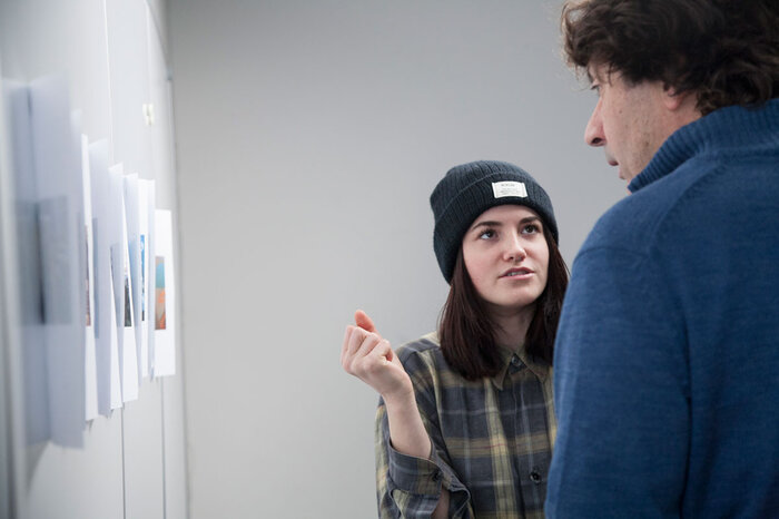 Zwei Studenten diskutieren über Fotos an der Wand. | © FHV