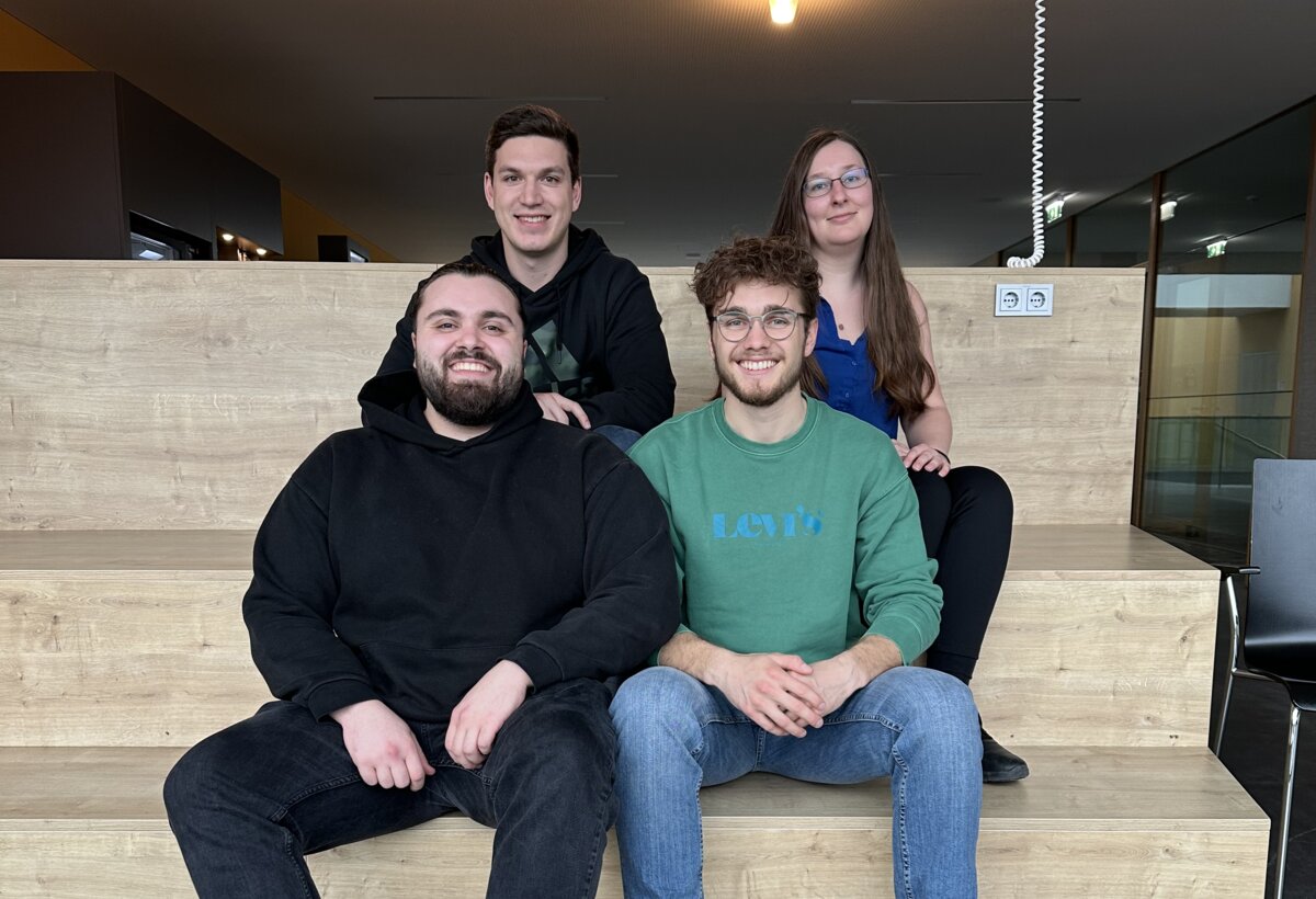 Vier Student:innen sitzen auf einer Treppe und posieren.  | © FHV