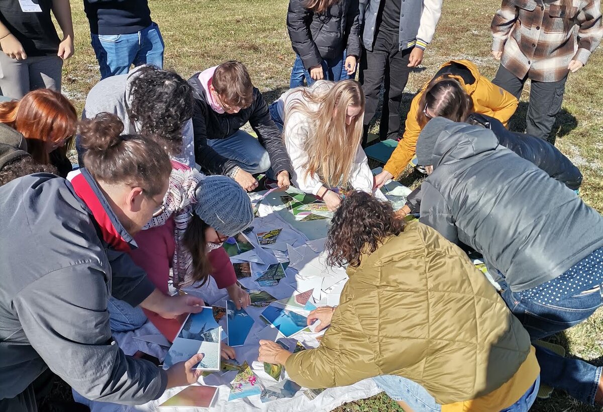 Gruppe Studierender beugt sich über Fotos auf einer Wiese | © ©fachbereich-gestaltung-fhv